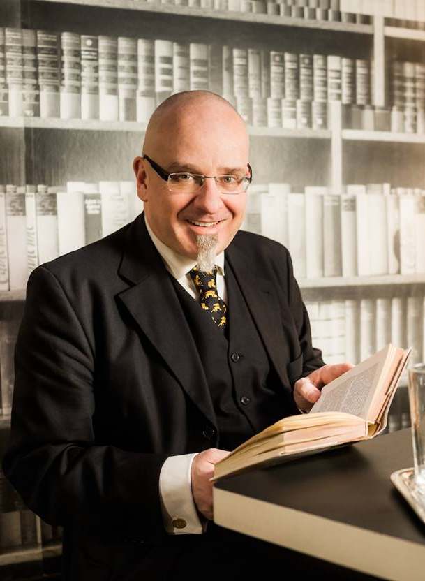 Gregor Oezelt mit Buch vor einer Bibliothek